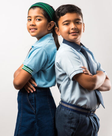 Cheerful Indian school kids in uniform standing isolated over white background