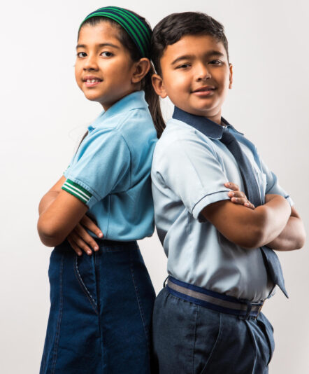 Cheerful Indian school kids in uniform standing isolated over white background