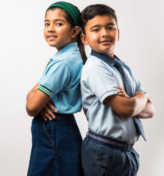 Cheerful Indian school kids in uniform standing isolated over white background