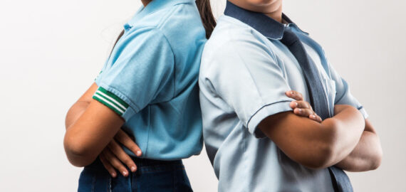 Cheerful Indian school kids in uniform standing isolated over white background