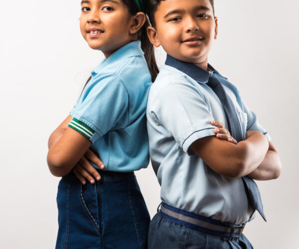 Cheerful Indian school kids in uniform standing isolated over white background