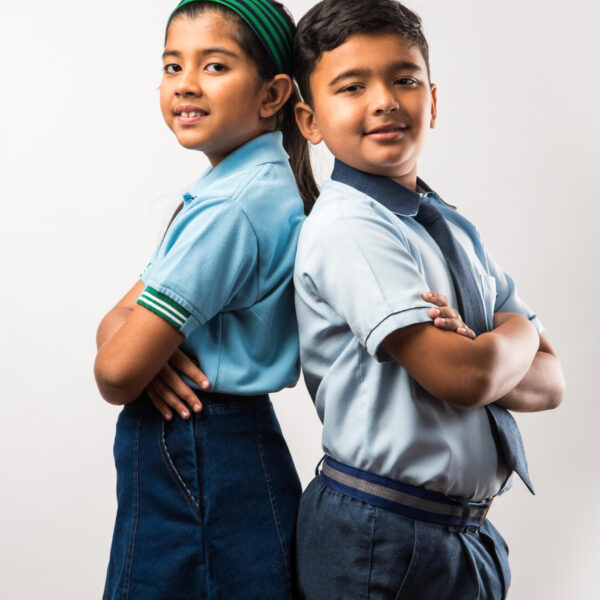 Cheerful Indian school kids in uniform standing isolated over white background