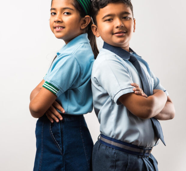Cheerful Indian school kids in uniform standing isolated over white background